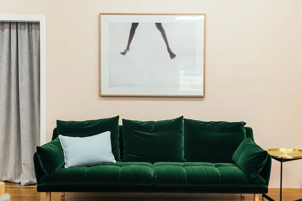 Salon décoré, canapé en velours vert sur mur clair avec cadres